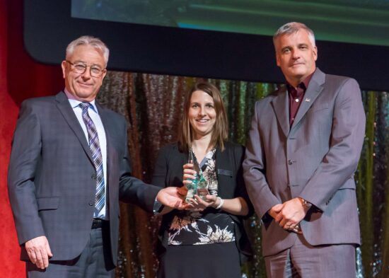 Consulting professionals holding an award at a public event