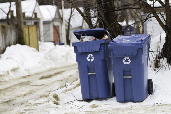 Blue waste bins in a residential back alley in the winter