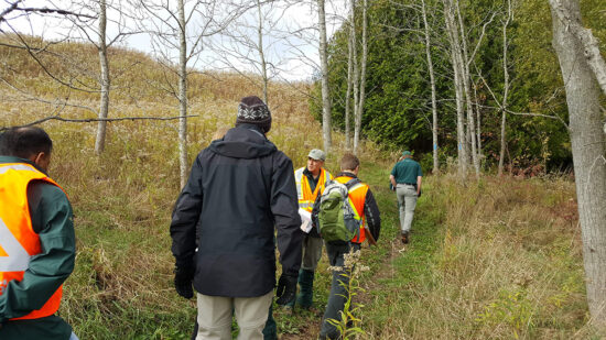 People in safety vests walking on trail of the park