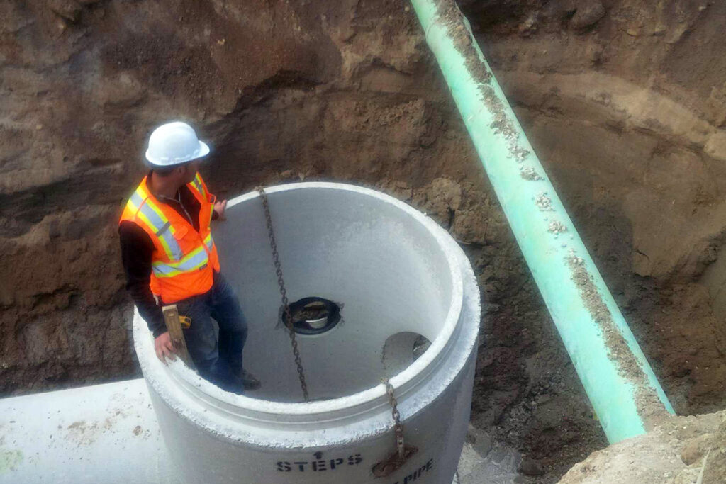 Man inside concrete tube installing sewer lines