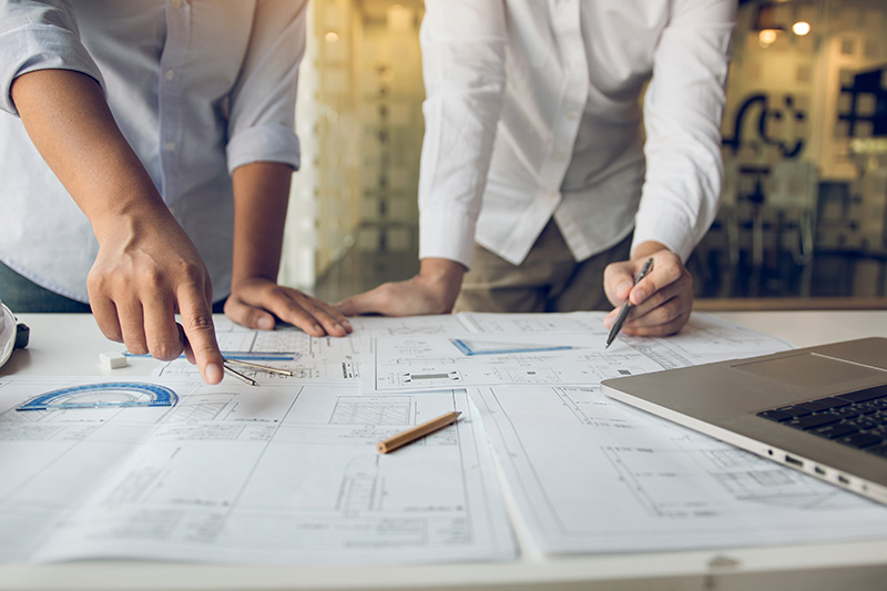 Two people going over building plans on a desk