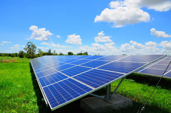 Solar panels under a blue sky with light cloud cover