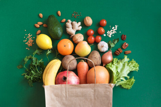stock photo of fruits nuts and vegetables spilling out of a paper bag