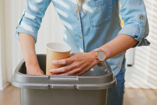 Woman putting paper cup in waste bin