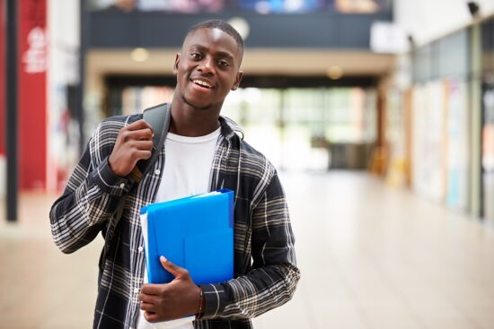 Portrait of a male student standing in college building