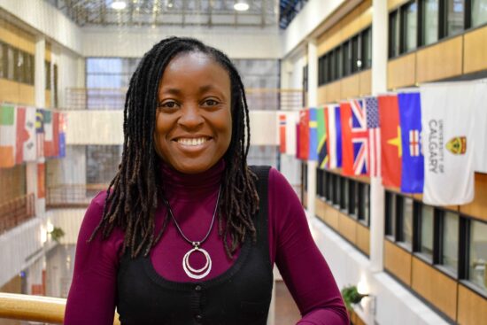 young woman standing in a hall decorated with various world flags