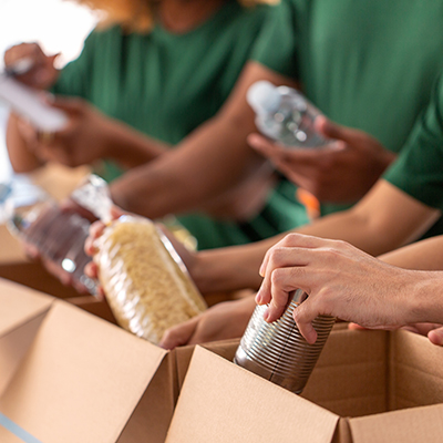 Hands putting donated food bank items into boxes.