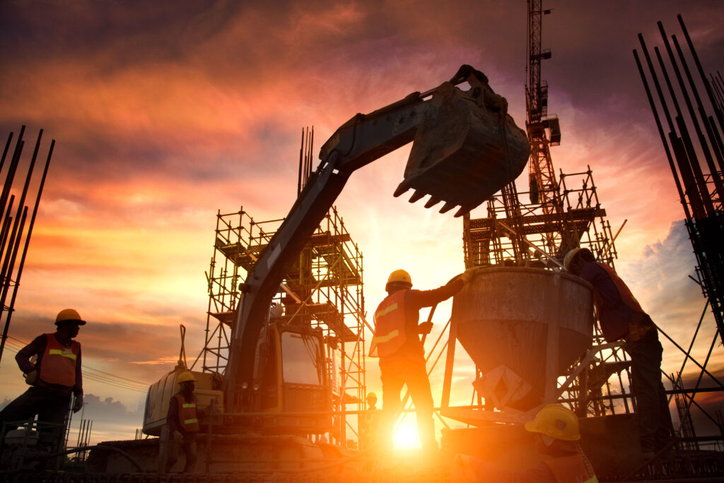 Construction team and heavy machinery against a sunset